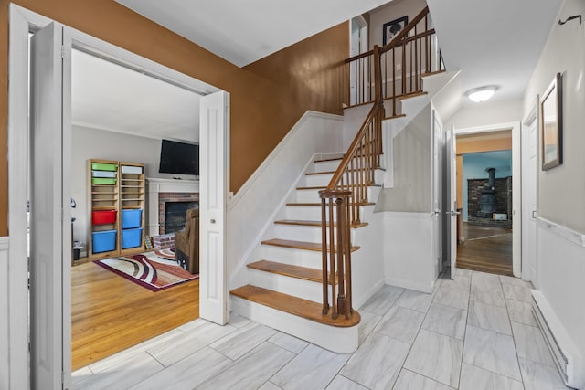 2 Judith Dr, Danbury, CT 06811 - stairs with a wood stove, a fireplace, a baseboard radiator, and a wainscoted wall
