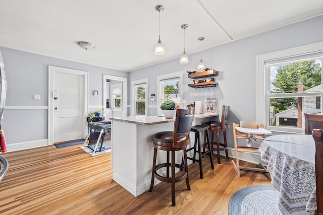 33 Hugh St, West Hartford, CT 06119 - kitchen featuring light wood finished floors, a peninsula, a kitchen bar, pendant lighting, and light stone countertops