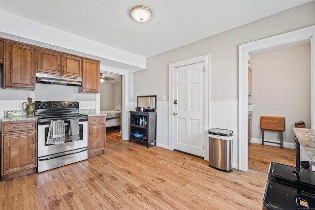 33 Hugh St, West Hartford, CT 06119 - kitchen with stainless steel range with electric cooktop, under cabinet range hood, light wood finished floors, brown cabinets, and wainscoting