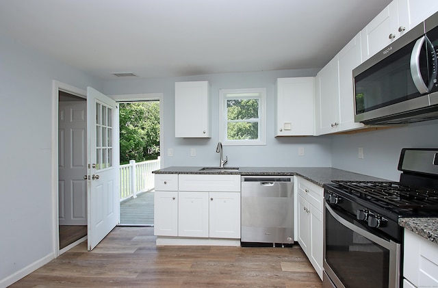 5 Golden Hill Ave, Danbury, CT 06811 - kitchen featuring appliances with stainless steel finishes, light wood finished floors, white cabinetry, and dark stone counters