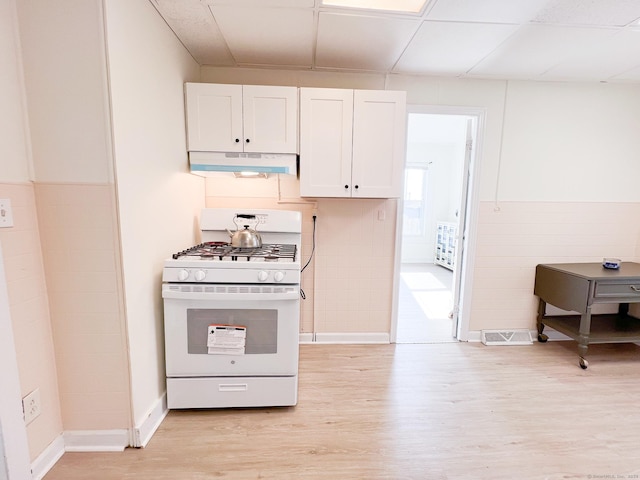 12 Arlington St, West Haven, CT 06516 - kitchen with white gas stove, under cabinet range hood, light wood-type flooring, white cabinets, and a paneled ceiling