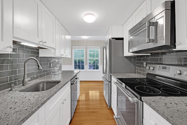 97 Park Ave Unit 70, Danbury, CT 06810 - kitchen with stainless steel appliances, light wood finished floors, white cabinetry, decorative backsplash, and light stone countertops