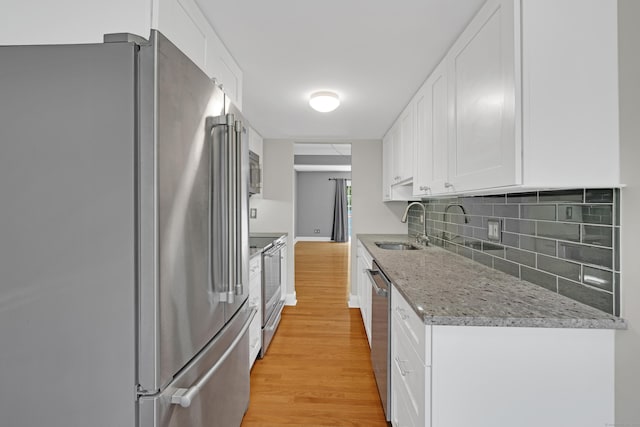 97 Park Ave Unit 70, Danbury, CT 06810 - kitchen with stainless steel appliances, light wood-style floors, decorative backsplash, white cabinets, and light stone counters