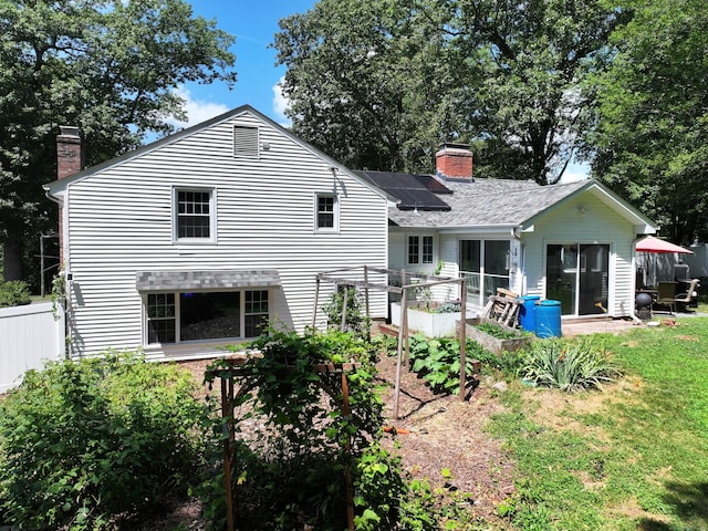 130 Olde Stage Rd, Glastonbury, CT 06033 - rear view of property featuring a chimney, solar panels, a sunroom, a shingled roof, and a garden