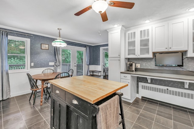680 Wheelers Farms Rd, Milford, CT 06461 - kitchen with radiator, wood counters, ornamental molding, dark tile patterned flooring, and white cabinets