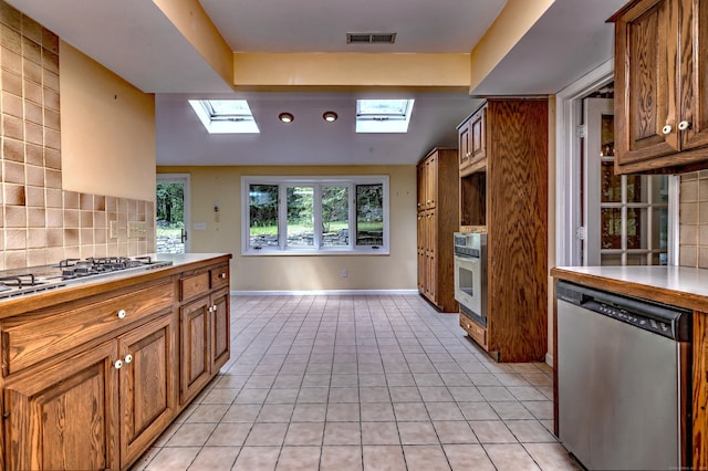 22 E Woods Rd, Roxbury, CT 06783 - kitchen featuring stainless steel appliances, a skylight, brown cabinets, backsplash, and lofted ceiling