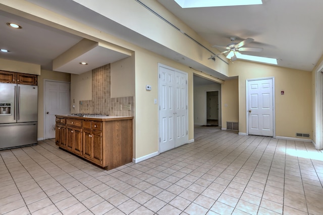 22 E Woods Rd, Roxbury, CT 06783 - kitchen with stainless steel appliances, a skylight, vaulted ceiling, brown cabinetry, and backsplash