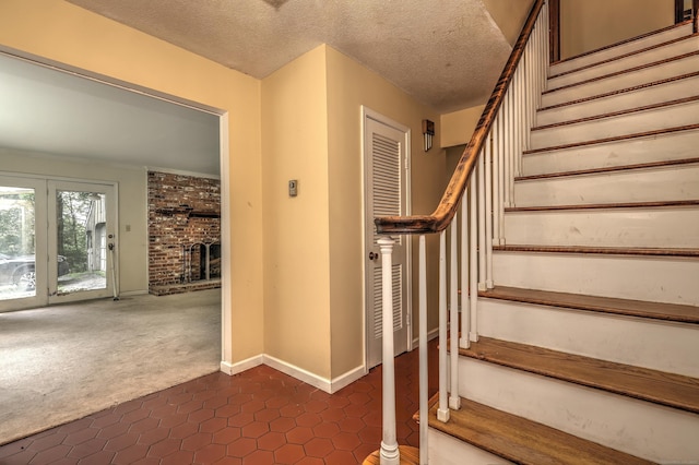22 E Woods Rd, Roxbury, CT 06783 - stairway with tile patterned floors, carpet floors, a brick fireplace, and a textured ceiling