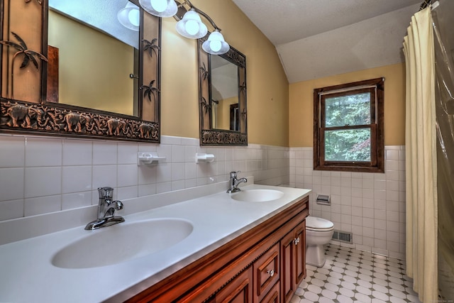 22 E Woods Rd, Roxbury, CT 06783 - bathroom featuring vaulted ceiling, tile walls, double vanity, and wainscoting