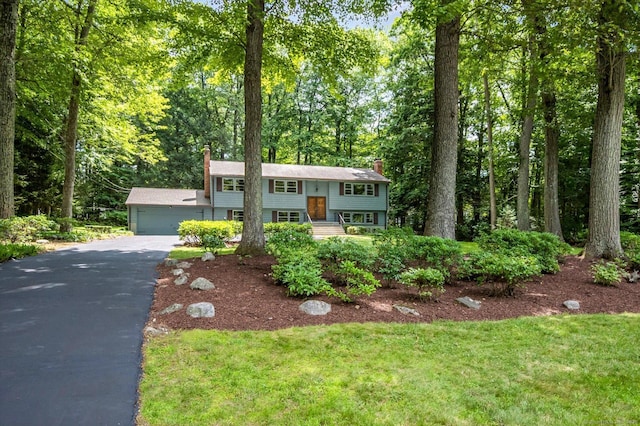 128 Carriage Dr, Avon, CT 06001 - raised ranch with a chimney, asphalt driveway, a garage, and a front lawn