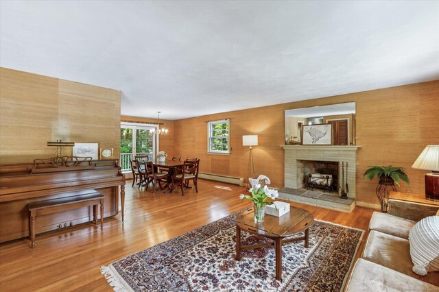 128 Carriage Dr, Avon, CT 06001 - living room with baseboard heating, light wood-style floors, a fireplace, and a chandelier
