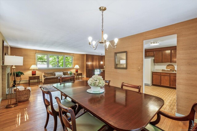 128 Carriage Dr, Avon, CT 06001 - dining room with a chandelier, wooden walls, light wood-style floors, and baseboard heating