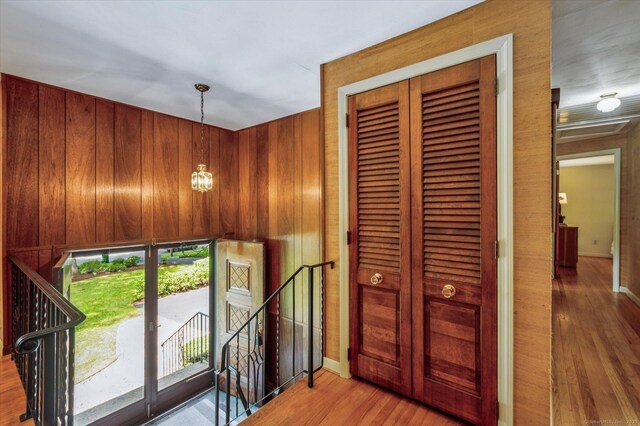 128 Carriage Dr, Avon, CT 06001 - hall featuring an upstairs landing, wood finished floors, wooden walls, and a chandelier