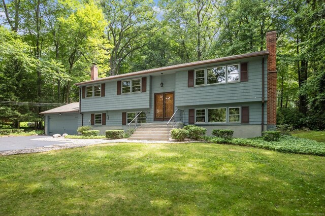 128 Carriage Dr, Avon, CT 06001 - split foyer home featuring a chimney, driveway, a front yard, and an attached garage