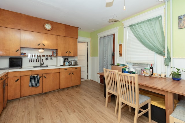 213 Easton Ave, Waterbury, CT 06704 - kitchen featuring light wood-style floors, light countertops, a wainscoted wall, and brown cabinets