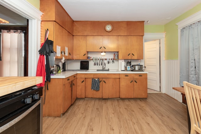 213 Easton Ave, Waterbury, CT 06704 - kitchen with light countertops, light wood-type flooring, wainscoting, and brown cabinetry