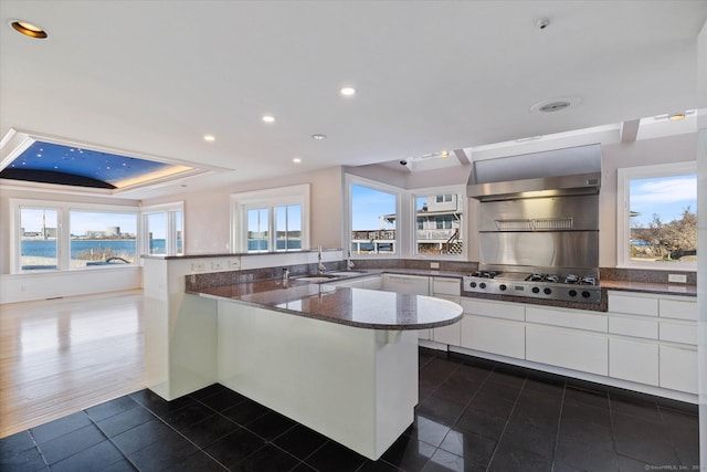 33 Palmer Rd, Waterford, CT 06385 - kitchen with a peninsula, stainless steel gas stovetop, dark tile patterned floors, white cabinets, and exhaust hood