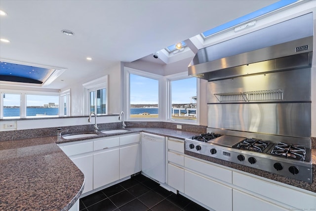 33 Palmer Rd, Waterford, CT 06385 - kitchen featuring white dishwasher, stainless steel gas stovetop, a skylight, dark tile patterned flooring, and white cabinetry