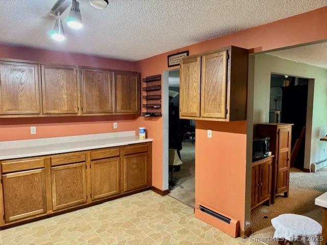 77 Plains Rd, Windham, CT 06280 - kitchen with a textured ceiling, brown cabinetry, and light countertops