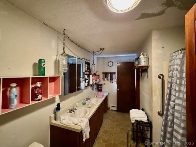 77 Plains Rd, Windham, CT 06280 - full bathroom with double vanity, a baseboard radiator, a textured ceiling, and a shower with shower curtain