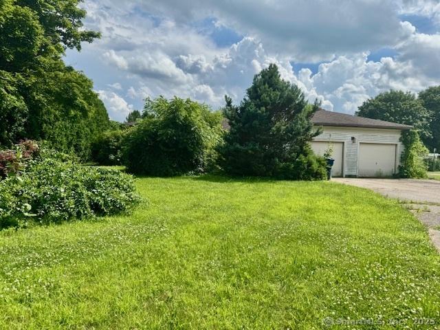 77 Plains Rd, Windham, CT 06280 - view of green lawn with asphalt driveway and a garage