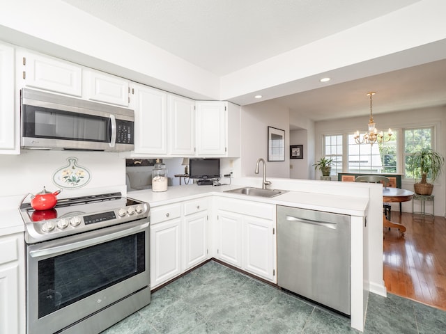 26 Wilton Crst Unit 26, Wilton, CT 06897 - kitchen featuring appliances with stainless steel finishes, a peninsula, light countertops, a chandelier, and white cabinetry
