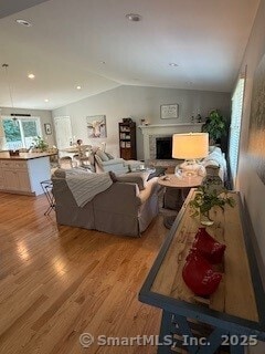 1 Brookfield Rd, Harwinton, CT 06791 - living room featuring wood finished floors, vaulted ceiling, and a fireplace with raised hearth