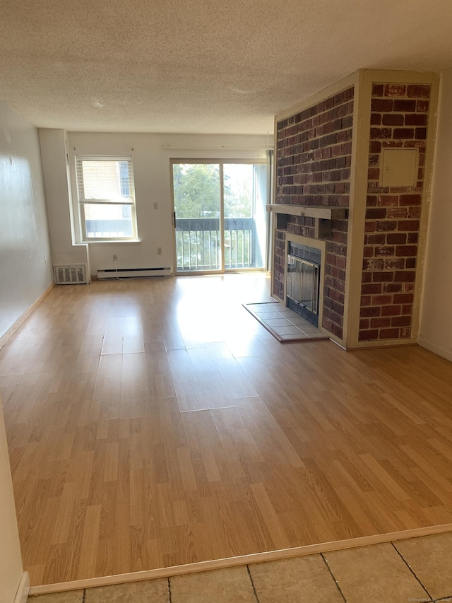 90 Kane St Apt C3, West Hartford, CT 06119 - unfurnished living room featuring baseboard heating, a brick fireplace, wood finished floors, and a textured ceiling