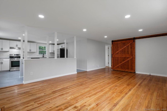 230 Green Rd, Manchester, CT 06042 - unfurnished living room featuring light wood-style floors, recessed lighting, and a barn door