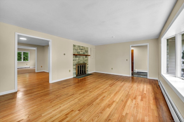 24 Iron Gate Ln, Cromwell, CT 06416 - unfurnished living room with a baseboard heating unit, light wood-style flooring, baseboard heating, and a stone fireplace