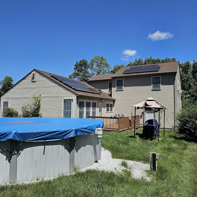 50 Meadow St, Meriden, CT 06451 - rear view of house with roof mounted solar panels, a wooden deck, a covered pool, and a lawn