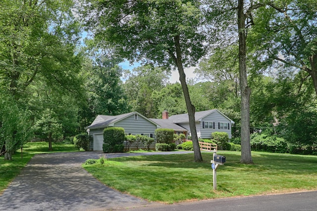 355 Surrey Ln, Fairfield, CT 06824 - split level home with asphalt driveway, a front yard, a garage, a chimney, and view of scattered trees