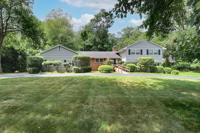 355 Surrey Ln, Fairfield, CT 06824 - tri-level home featuring a chimney, a front yard, brick siding, and view of scattered trees