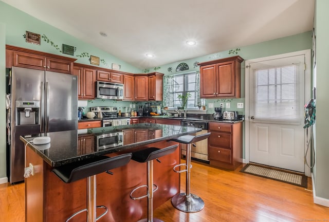 4 Wintergreen Ln, Naugatuck, CT 06770 - kitchen with appliances with stainless steel finishes, a breakfast bar area, light wood-style floors, lofted ceiling, and a kitchen island