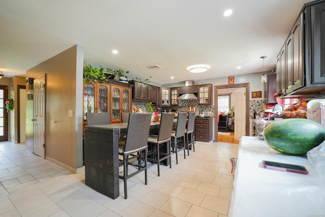 22 Standish Rd, New Milford, CT 06776 - kitchen featuring a breakfast bar, glass insert cabinets, tasteful backsplash, wall chimney range hood, and recessed lighting