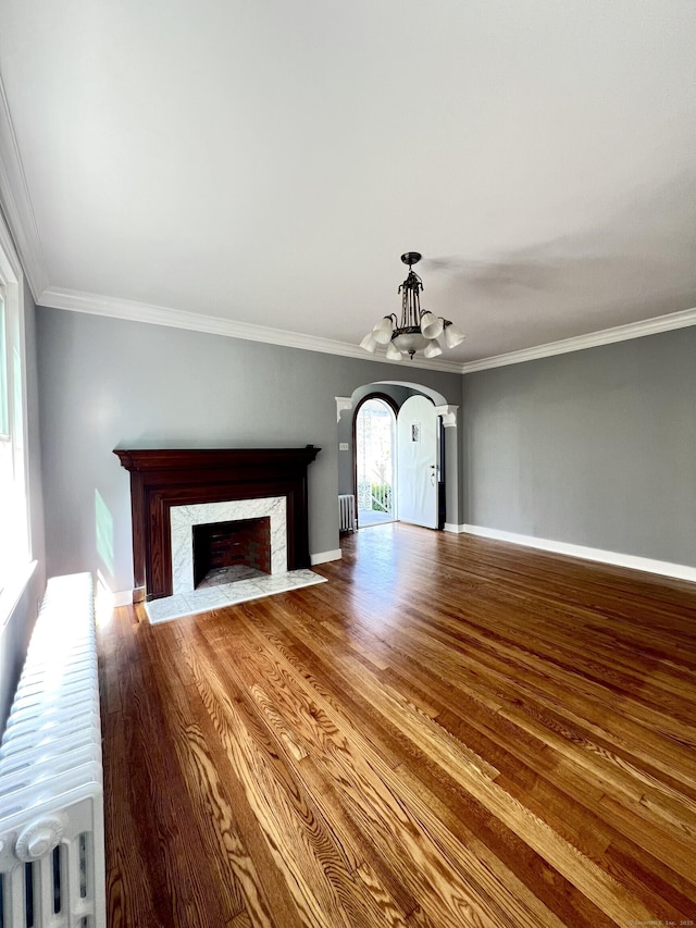50 Norman St, Waterbury, CT 06708 - unfurnished living room with arched walkways, a chandelier, a premium fireplace, wood finished floors, and crown molding