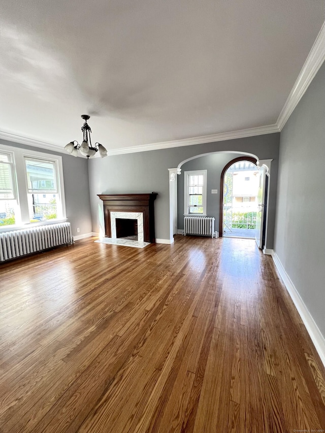 50 Norman St, Waterbury, CT 06708 - unfurnished living room with radiator heating unit, arched walkways, a chandelier, healthy amount of natural light, and ornamental molding