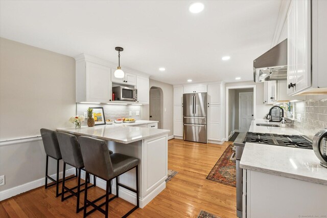 10 Craigmoor Rd, West Hartford, CT 06107 - kitchen featuring stainless steel appliances, wall chimney exhaust hood, arched walkways, a peninsula, and backsplash
