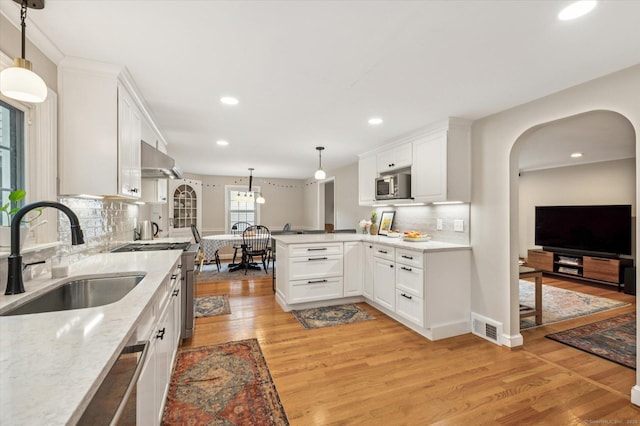 10 Craigmoor Rd, West Hartford, CT 06107 - kitchen with stainless steel microwave, a peninsula, light wood finished floors, backsplash, and white cabinets