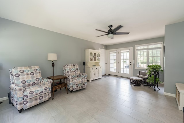 living area featuring ceiling fan and baseboards