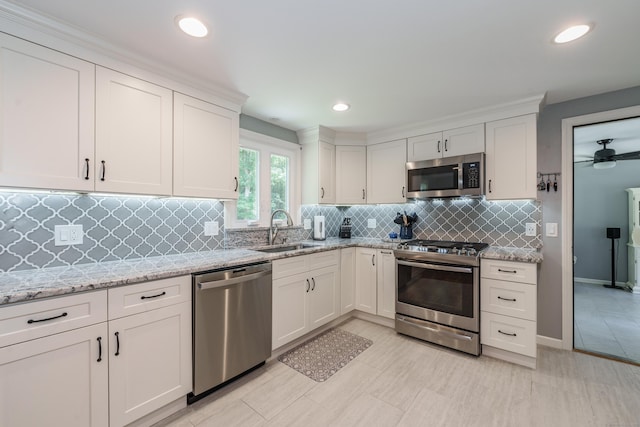 kitchen with stainless steel appliances, white cabinets, decorative backsplash, light stone counters, and recessed lighting