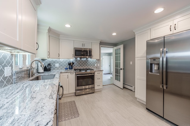 kitchen with stainless steel appliances, a baseboard radiator, decorative backsplash, light stone countertops, and recessed lighting