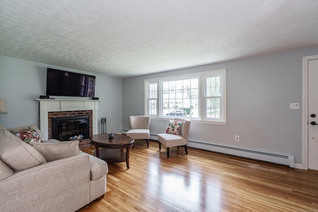living room with a baseboard radiator, a brick fireplace, and light wood-type flooring
