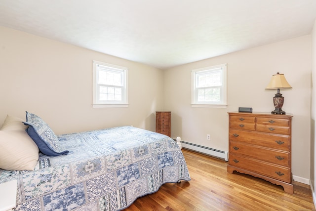 bedroom featuring baseboard heating, multiple windows, and wood finished floors