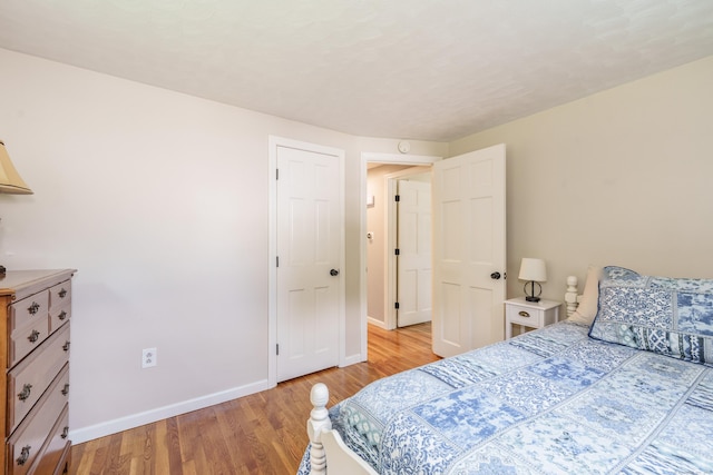 bedroom with light wood finished floors and baseboards