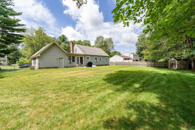 rear view of house featuring a chimney, a shed, and a fenced backyard