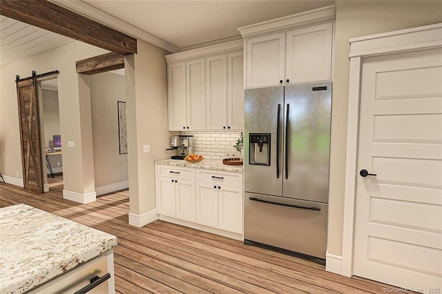 365 Cranberry Bog Rd, Killingly, CT 06239 - kitchen featuring stainless steel refrigerator with ice dispenser, a barn door, light wood-style flooring, decorative backsplash, and light stone countertops