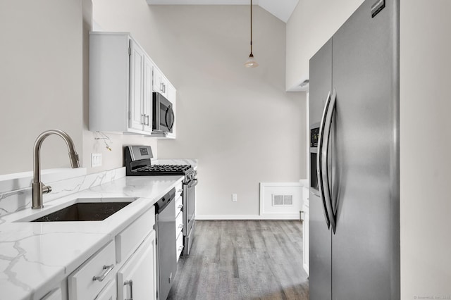 233 Mansfield Grove Rd Unit 306, East Haven, CT 06512 - kitchen featuring appliances with stainless steel finishes, pendant lighting, light wood-type flooring, light stone counters, and white cabinetry
