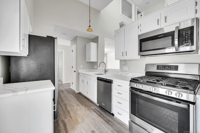 233 Mansfield Grove Rd Unit 306, East Haven, CT 06512 - kitchen with appliances with stainless steel finishes, light wood finished floors, white cabinetry, and a towering ceiling