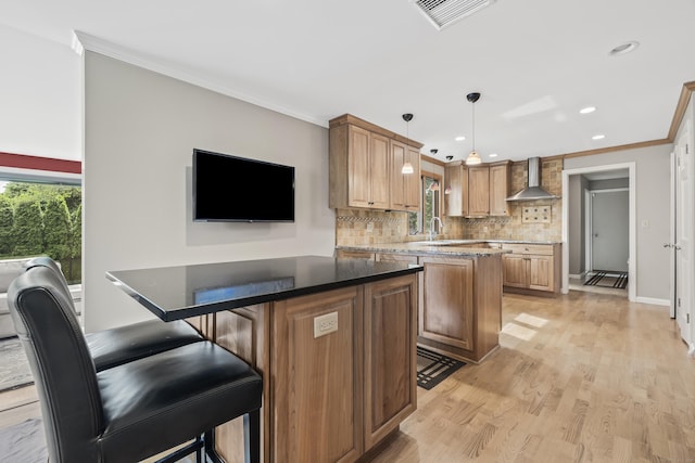1182 N Main St, West Hartford, CT 06117 - kitchen featuring a kitchen island, wall chimney exhaust hood, ornamental molding, backsplash, and light wood finished floors
